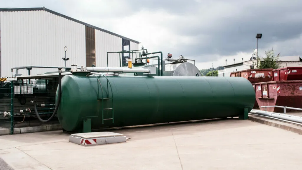 Grüner Öltank nach AwSV geprüft auf einem Betriebshof neben einer Halle