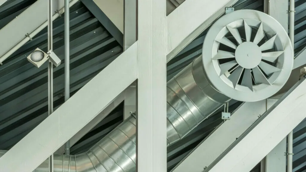 Verrohrung einer Lüftungsanlage mit großem Ventilator an einem Dach in einer Industriehalle